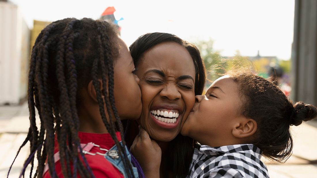 young daughters kissing mom on cheek