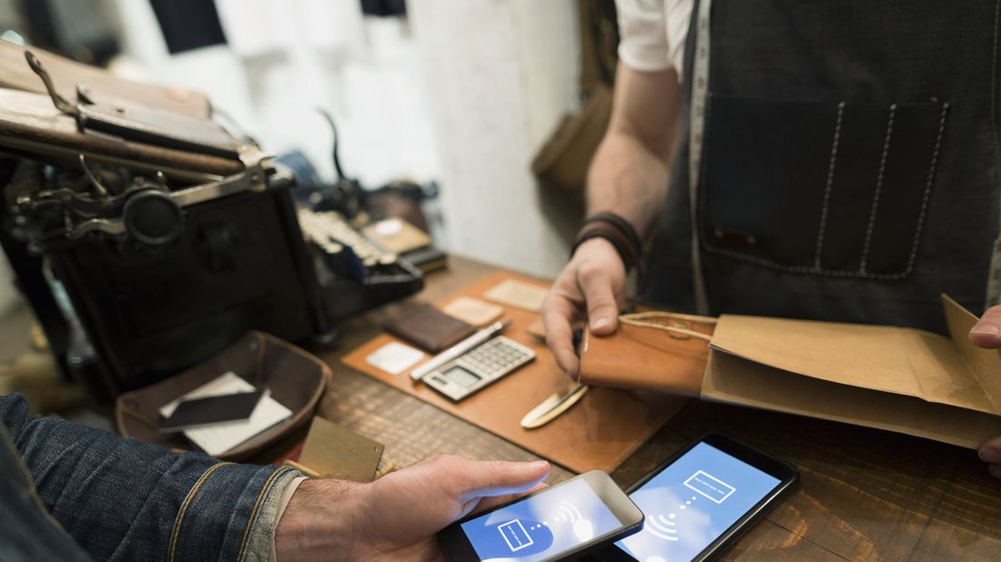 A customer uses smartphone to make a cashless purchase at small business