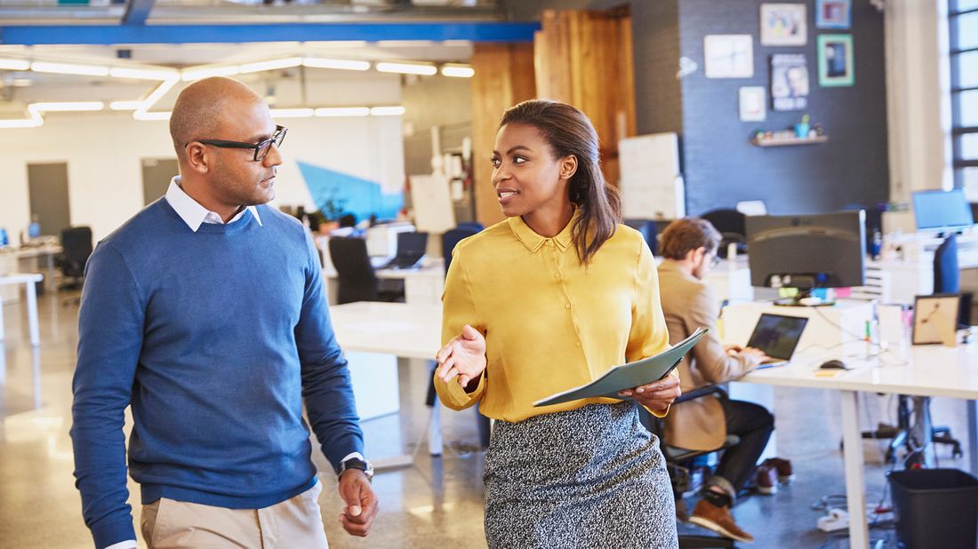 Man and woman walking together at work discussing a six-figure salary.