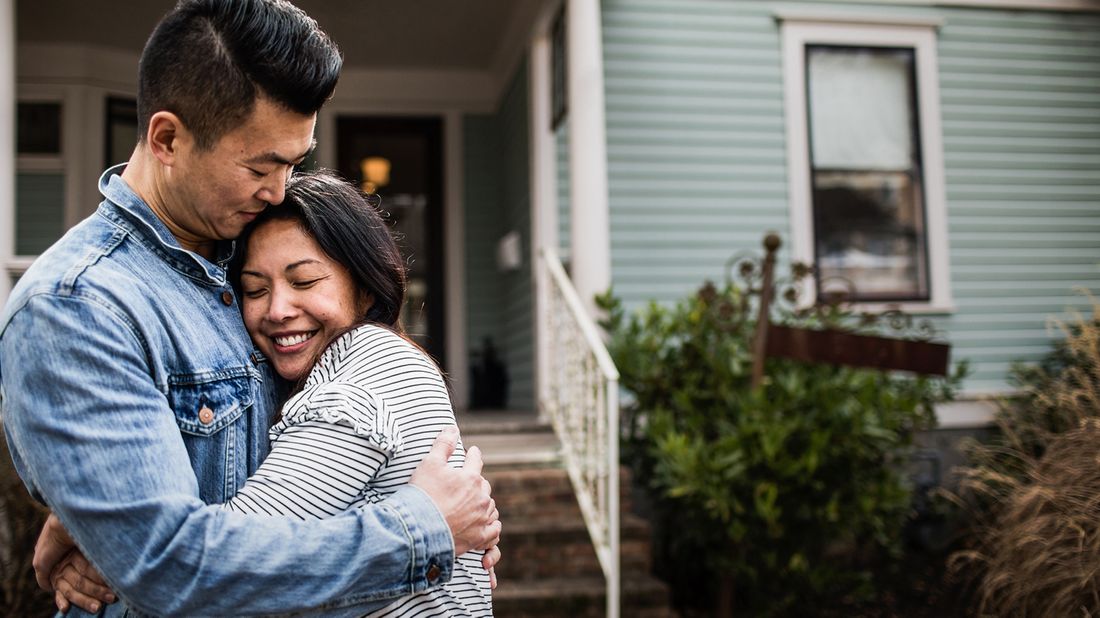 Young couple hugging in front of new home