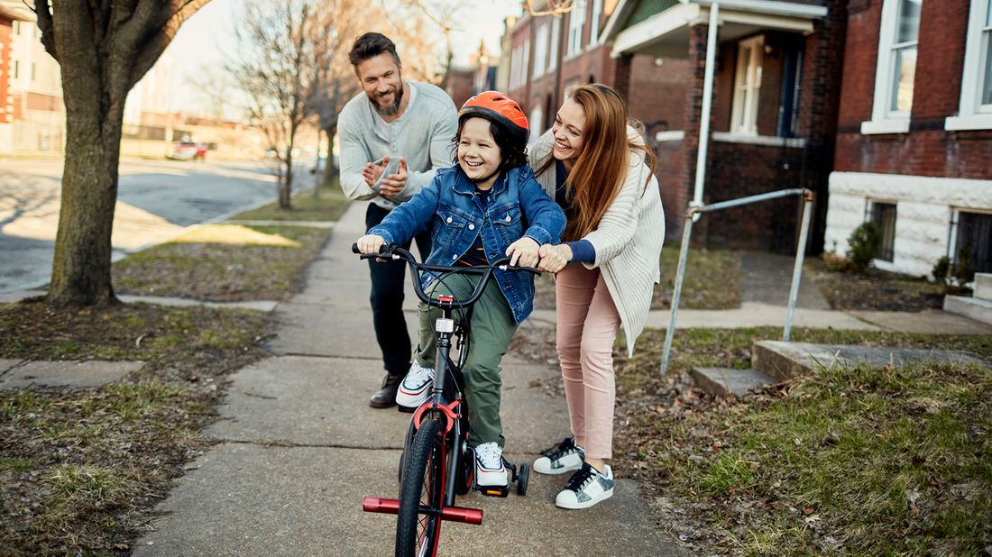 Mom and dad pushing child on a bike, pondering who should be the trustee and guardian for their child. 