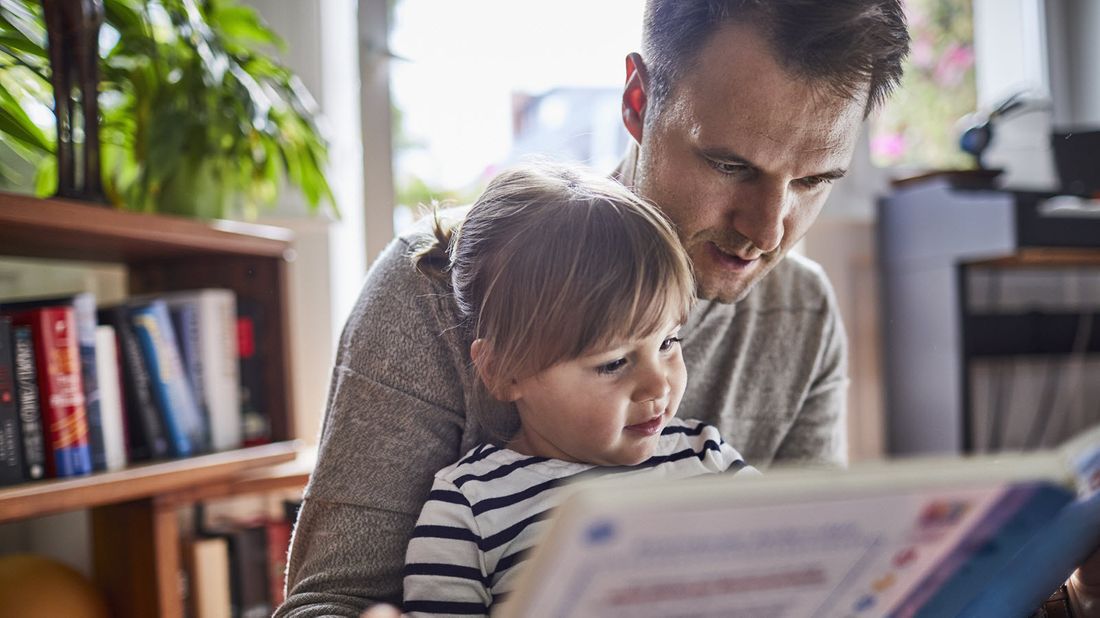 A father reading a book to his young daughter