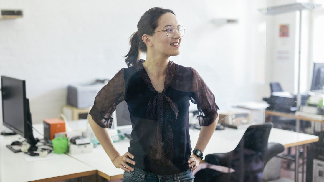 A woman standing in office smiling about group life insurance policy