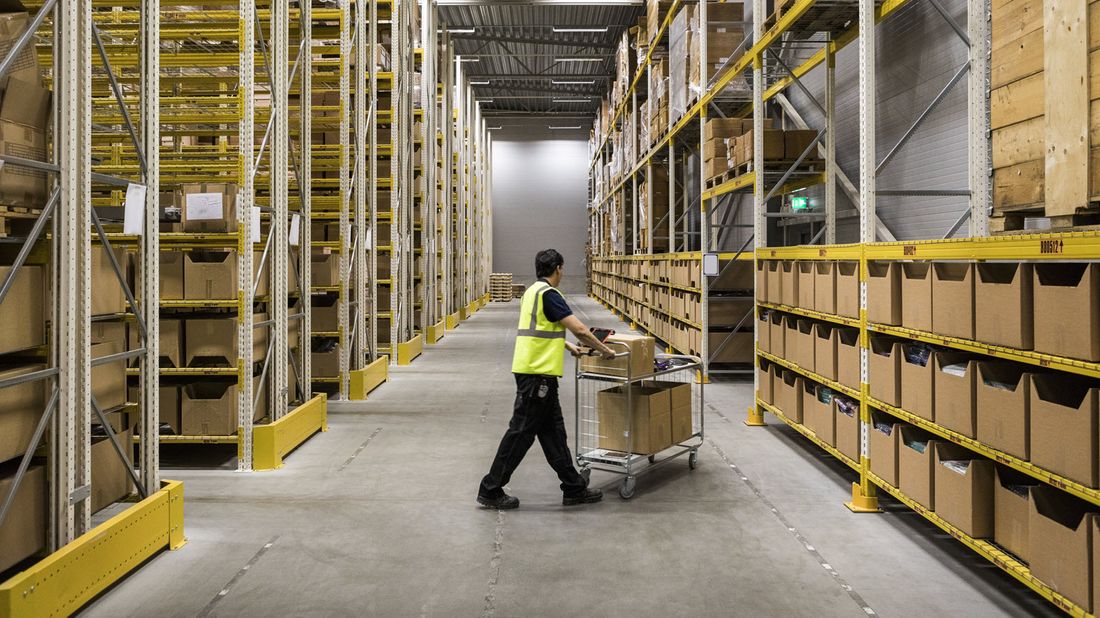 A warehouse worker at risk of automation moves goods on cart