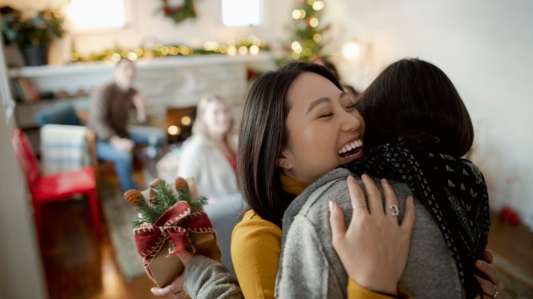 Friends hugging in new holiday tradition that helps save money.