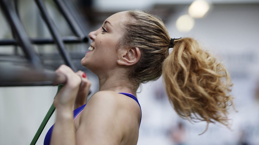 A woman doing chin-ups and accomplishing her resolutions 