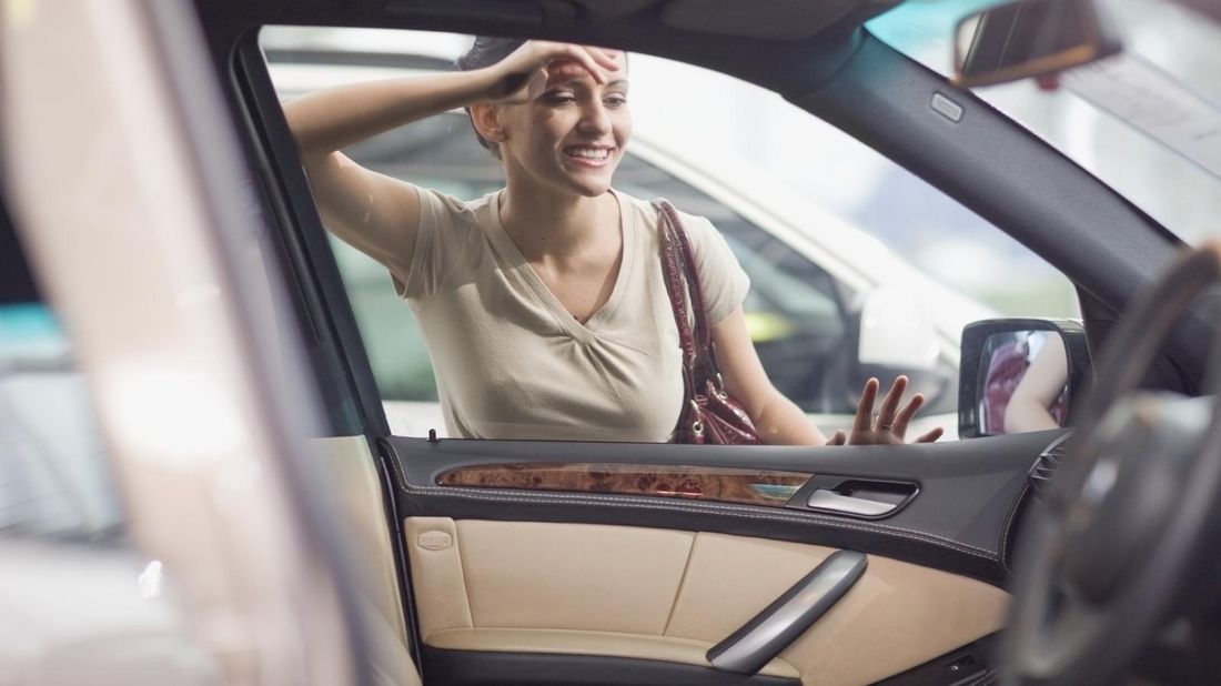 woman-looking-into-car-on-dealer-lot