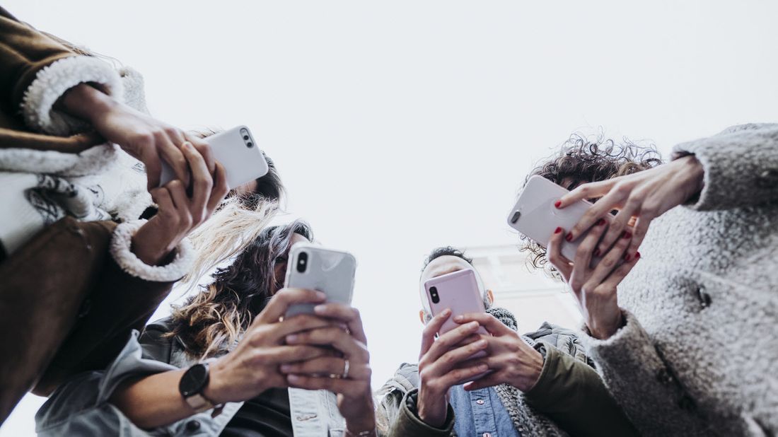 Teens checking social media on their smartphones