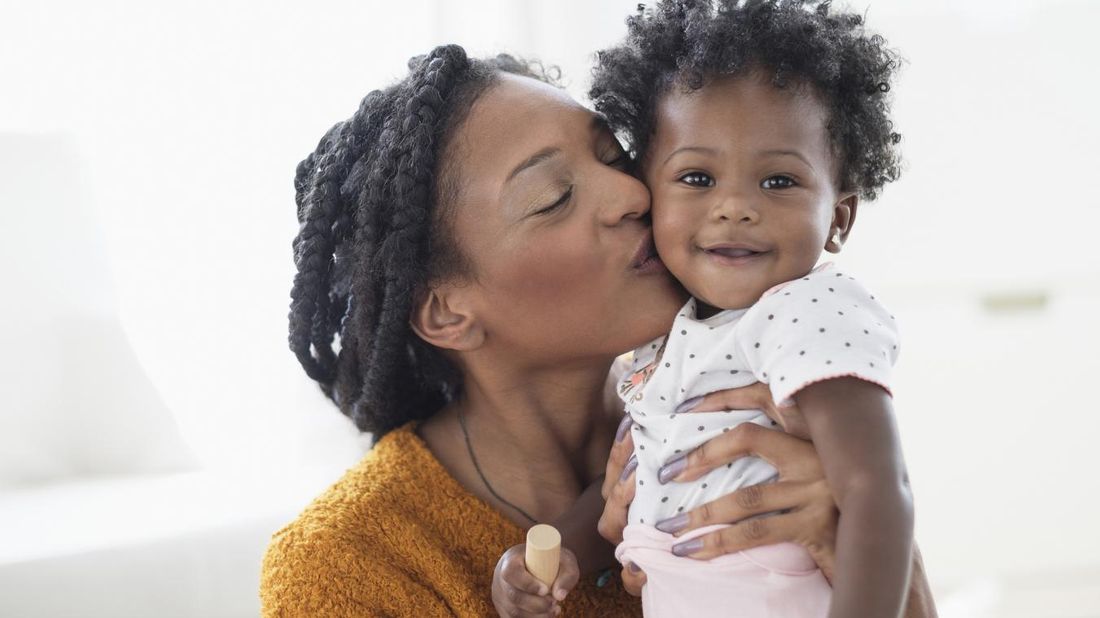 Mother kissing smiling baby on the cheek