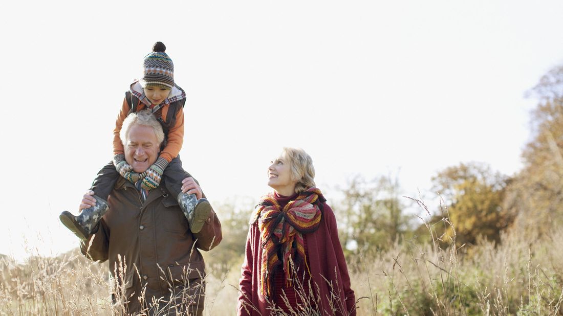 Man and woman walking with their grandchild as they discuss the pros and cons of gifting an estate before death