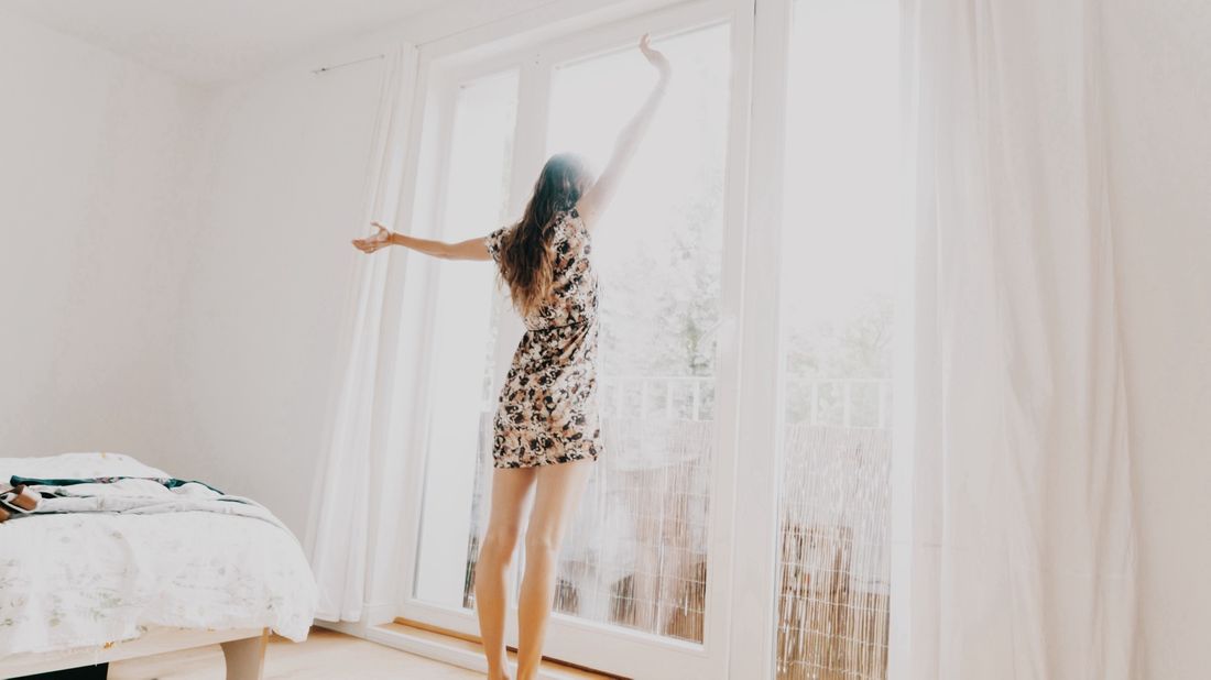 Woman standing on her bed looking out the window