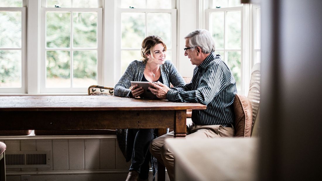 adult daughter and father sitting at home using a tablet