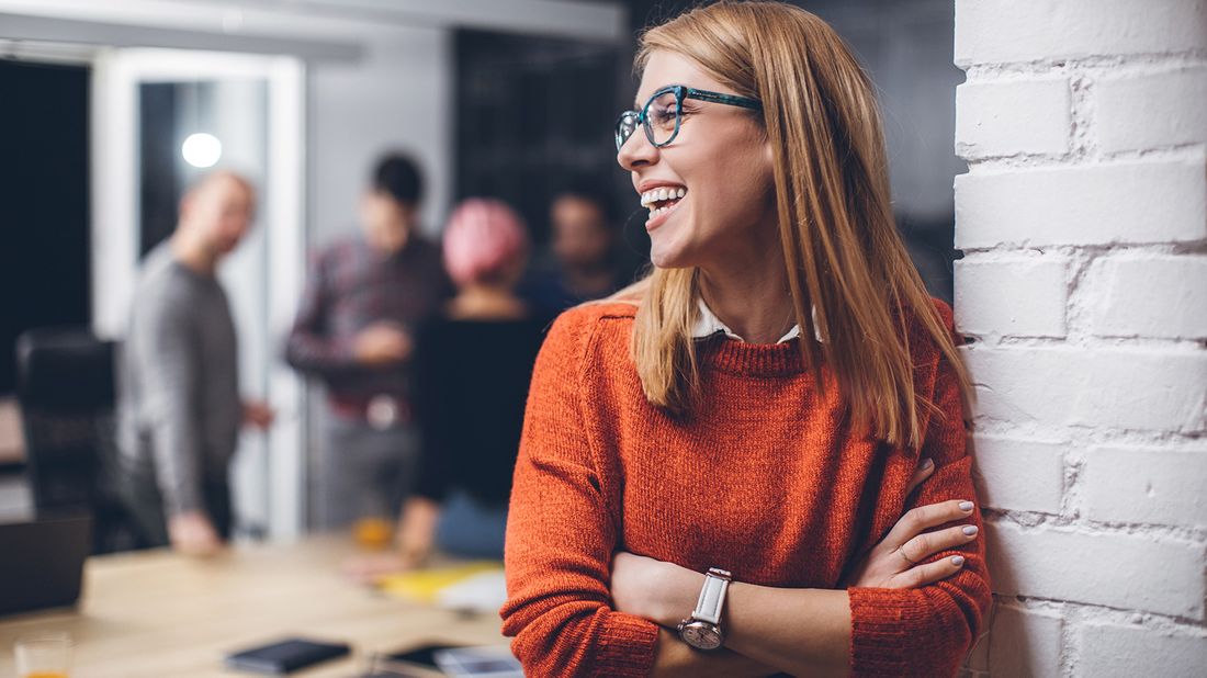 Happy woman at work thinking about career goals.