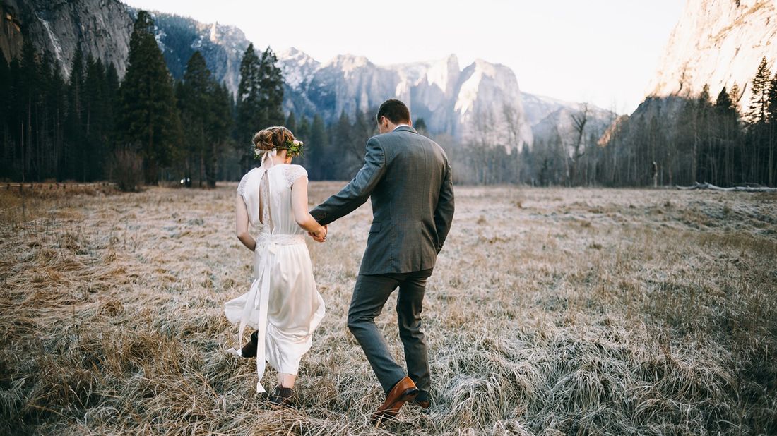 newlyweds walking toward mountains