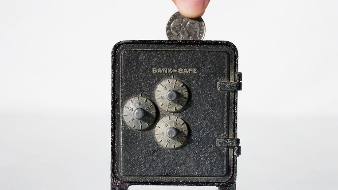 Fingers putting change in a bank safe