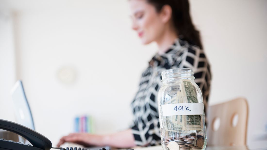 401k money jar on desk of young businesswoman