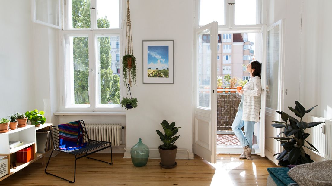 Woman at home standing at balcony door