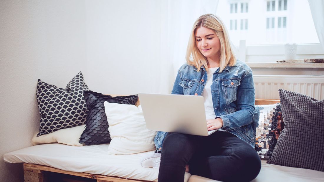 woman sitting on bed with her computer