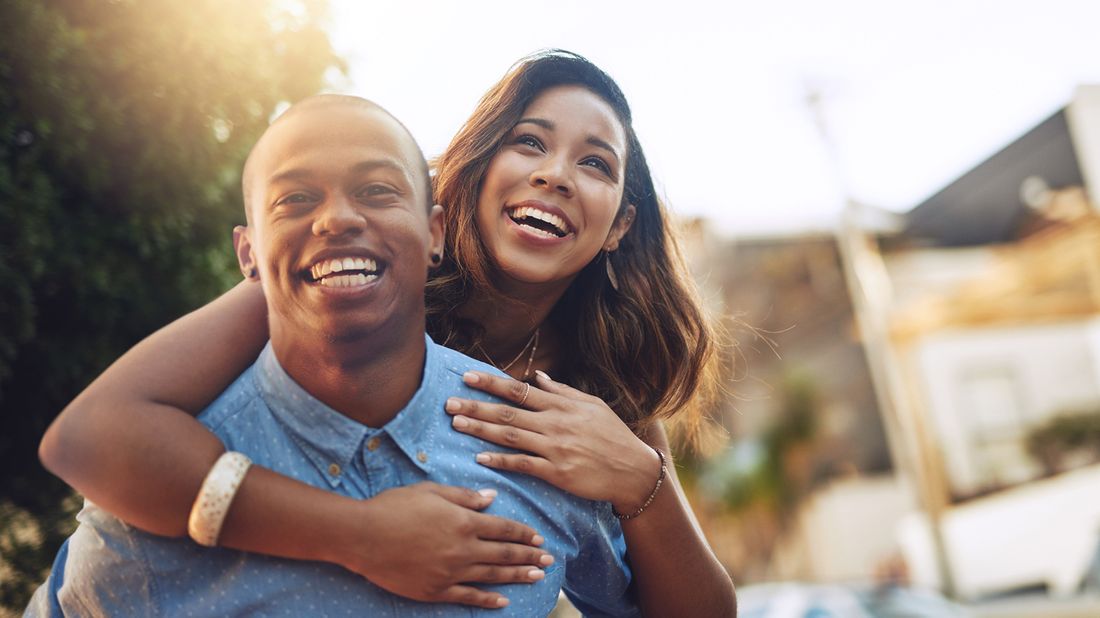 smiling young couple enjoying a piggyback ride