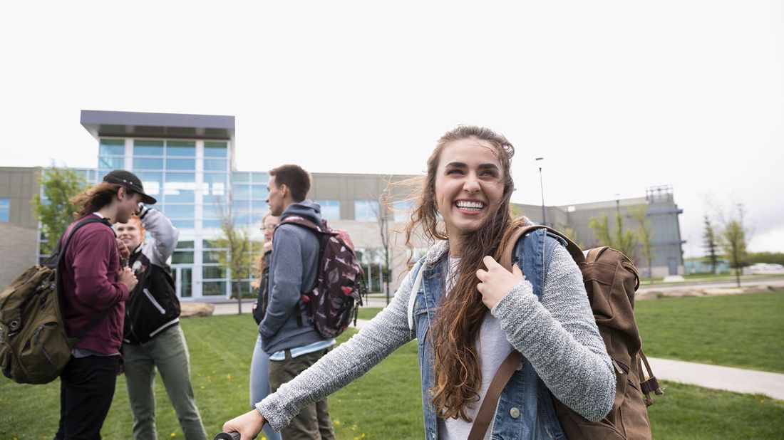 Young female college student smiling and walking on campus. 