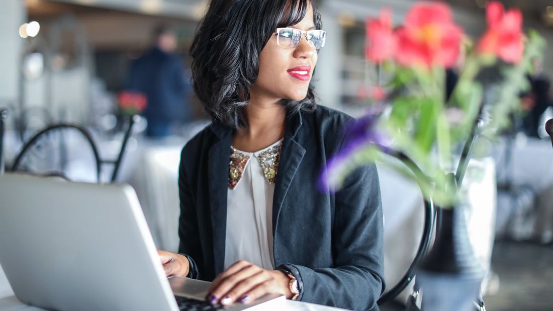 Woman working on a computer and looking into the distance.