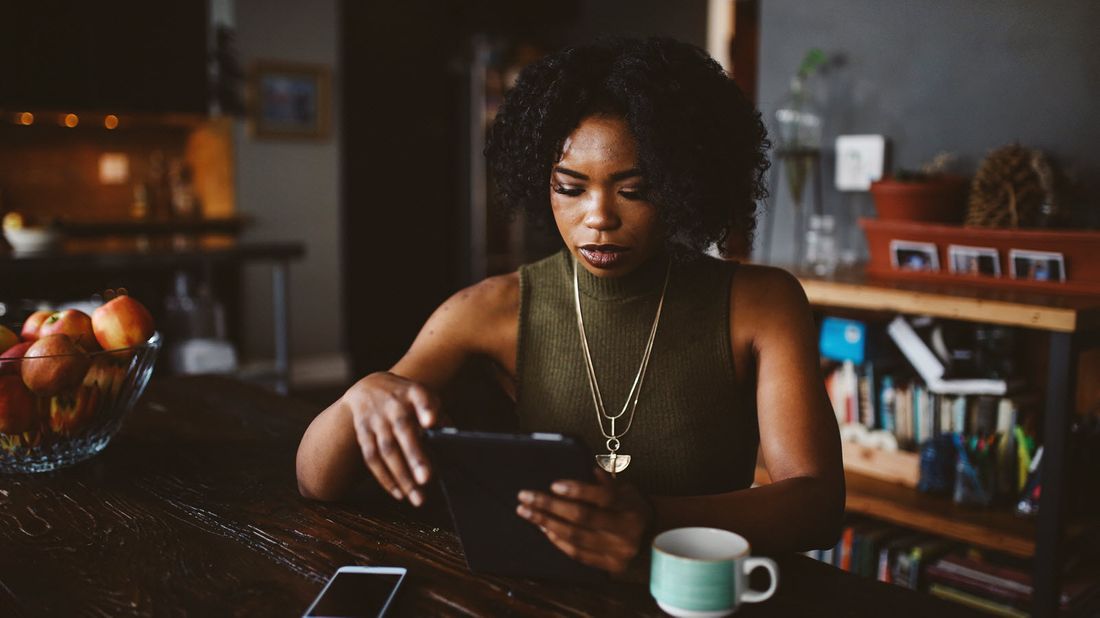 Woman drinking coffee and reading Northwestern Mutual Market Commentary