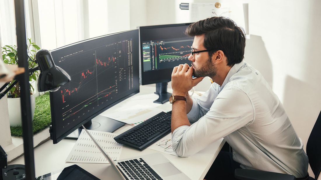 Man looking at data on multiple computer screens.