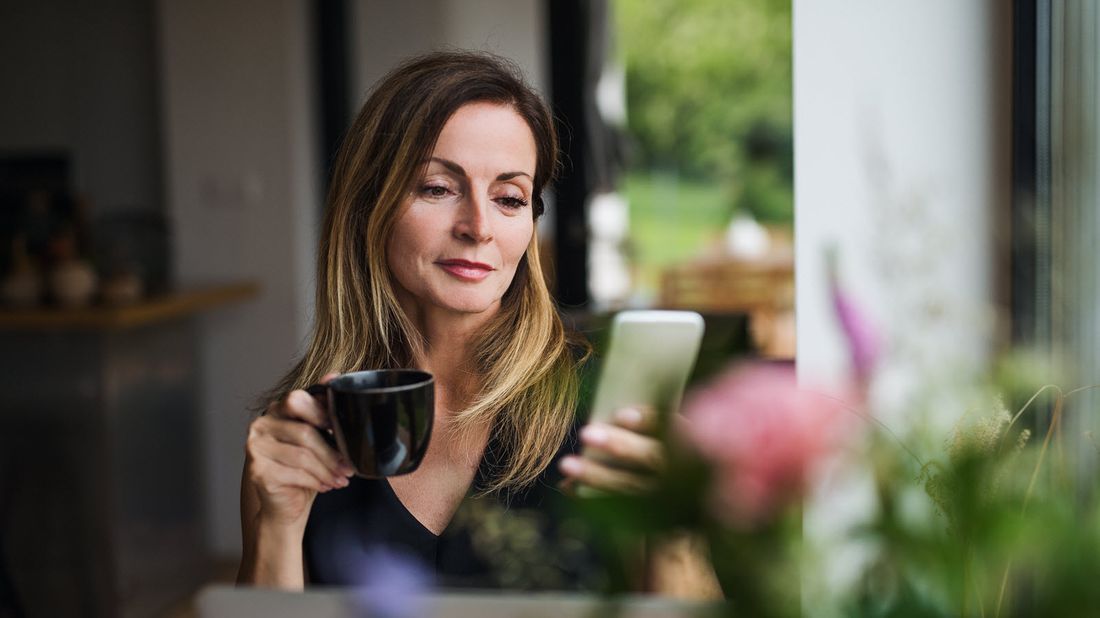 Woman drinking coffee and reading Northwestern Mutual Market Commentary.