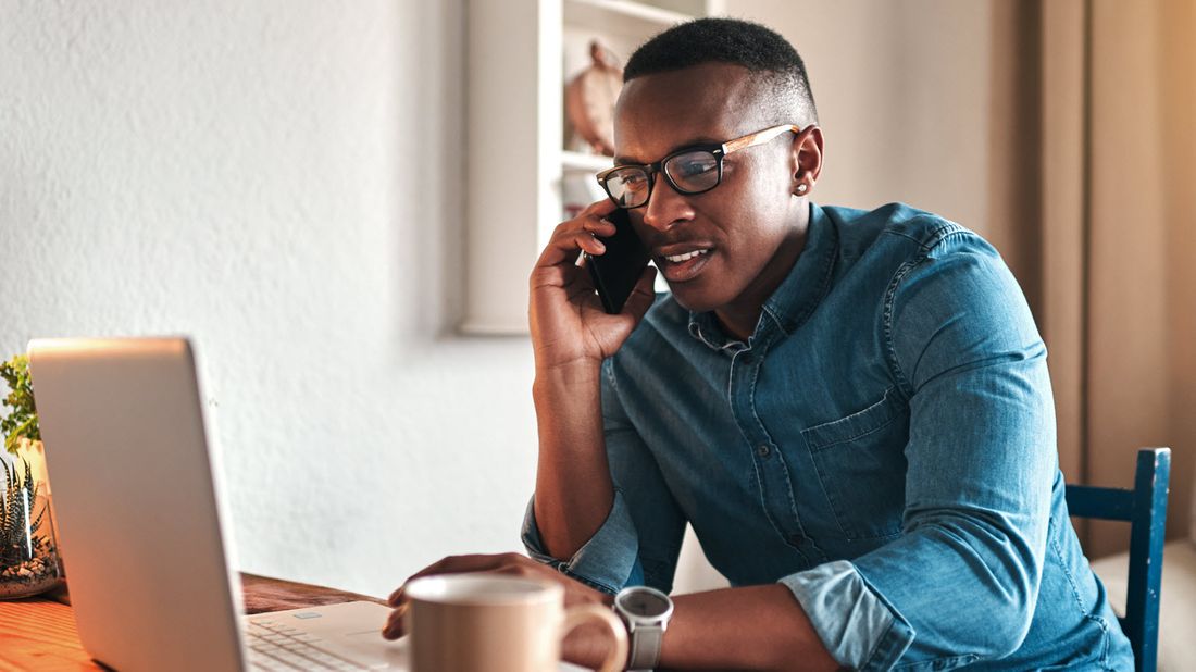 Man talking on the phone while looking at computer screen.