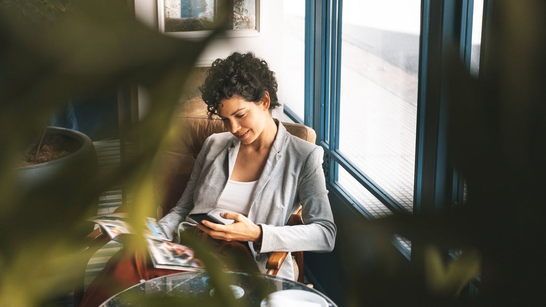 Woman sitting in a chair reading Northwestern Mutual Market Commentary.