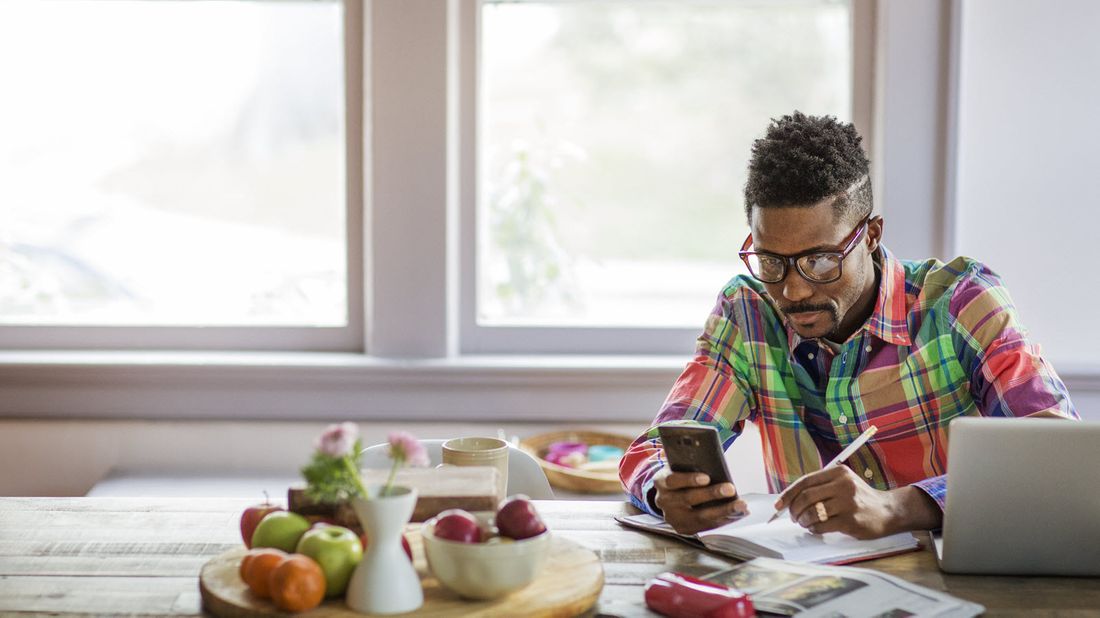 Man at table reading Northwestern Mutual Market Commentary on his phone