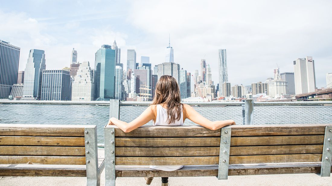 woman on bench looking at nyc skyline