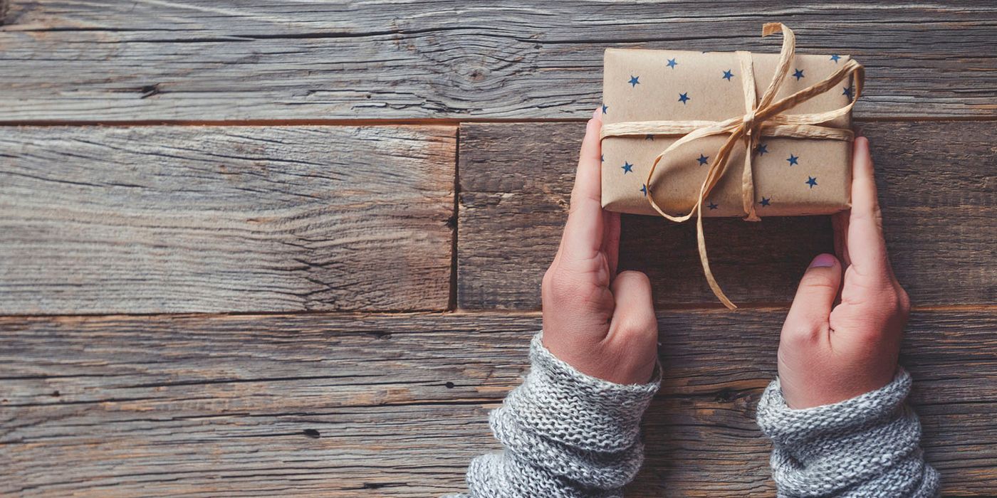 hands holding homemade gift box on wooden table