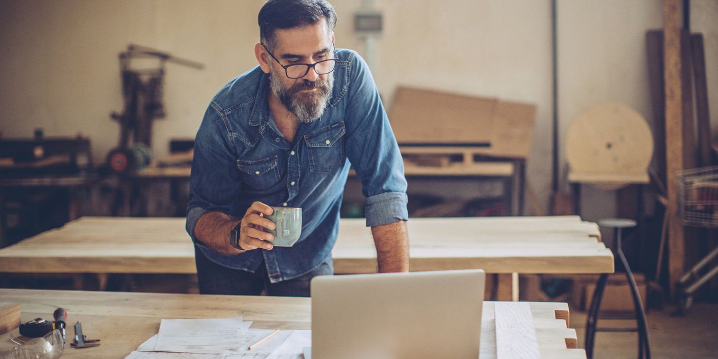 man looking at laptop while working in workshop