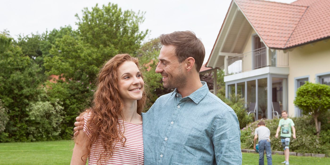smiling couple in garden with kids in background