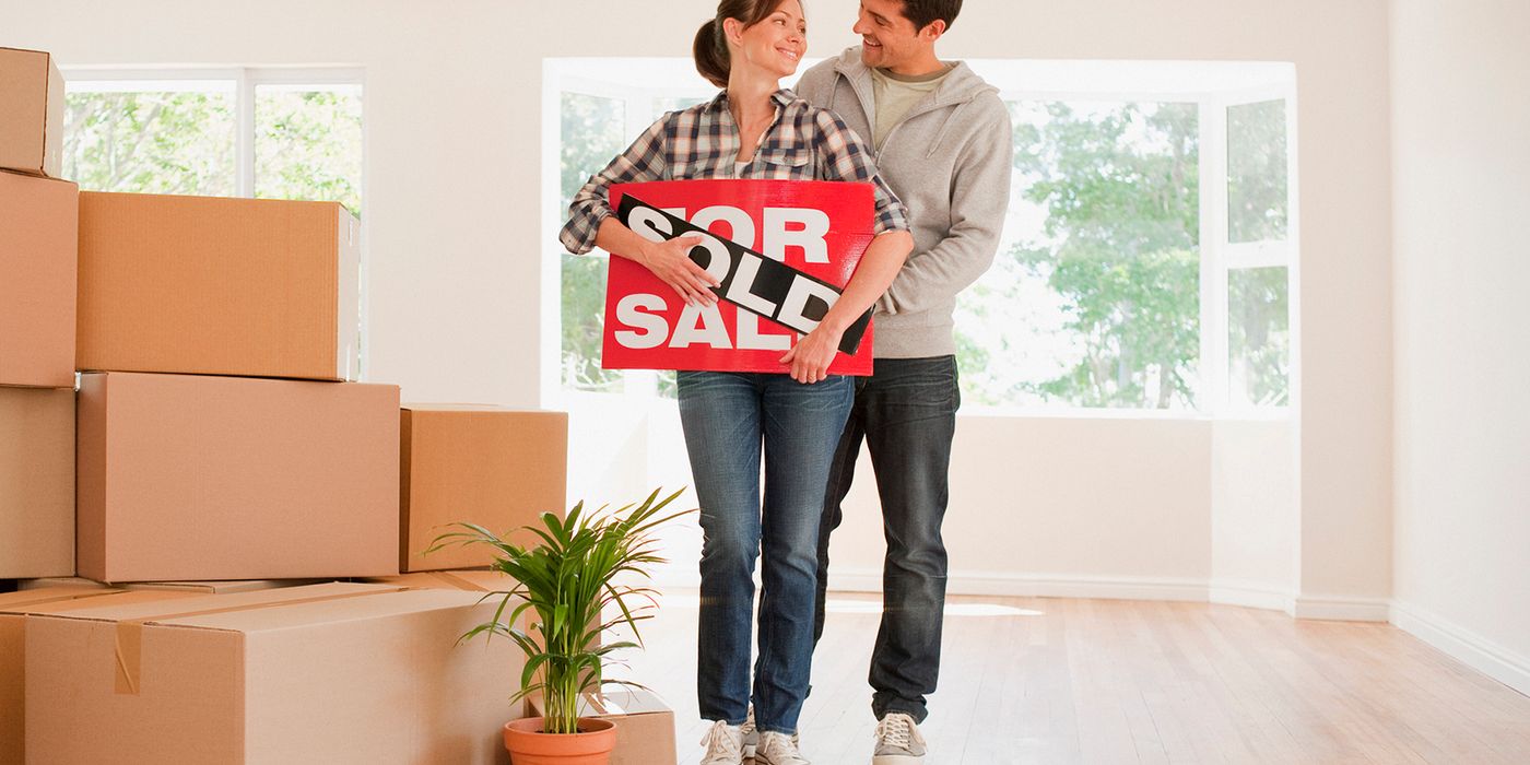 Couple holding sold sign after winning a bidding war.