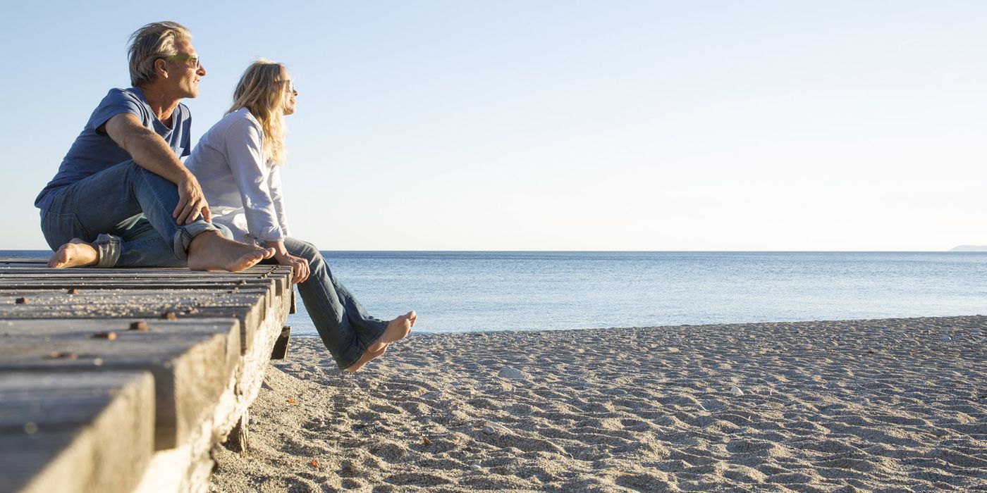 Couple sitting on a pier at a beach wondering how an annuity is taxed.