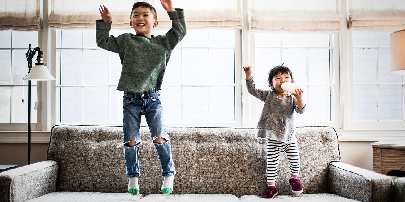 brother and sister jumping on the couch playfully