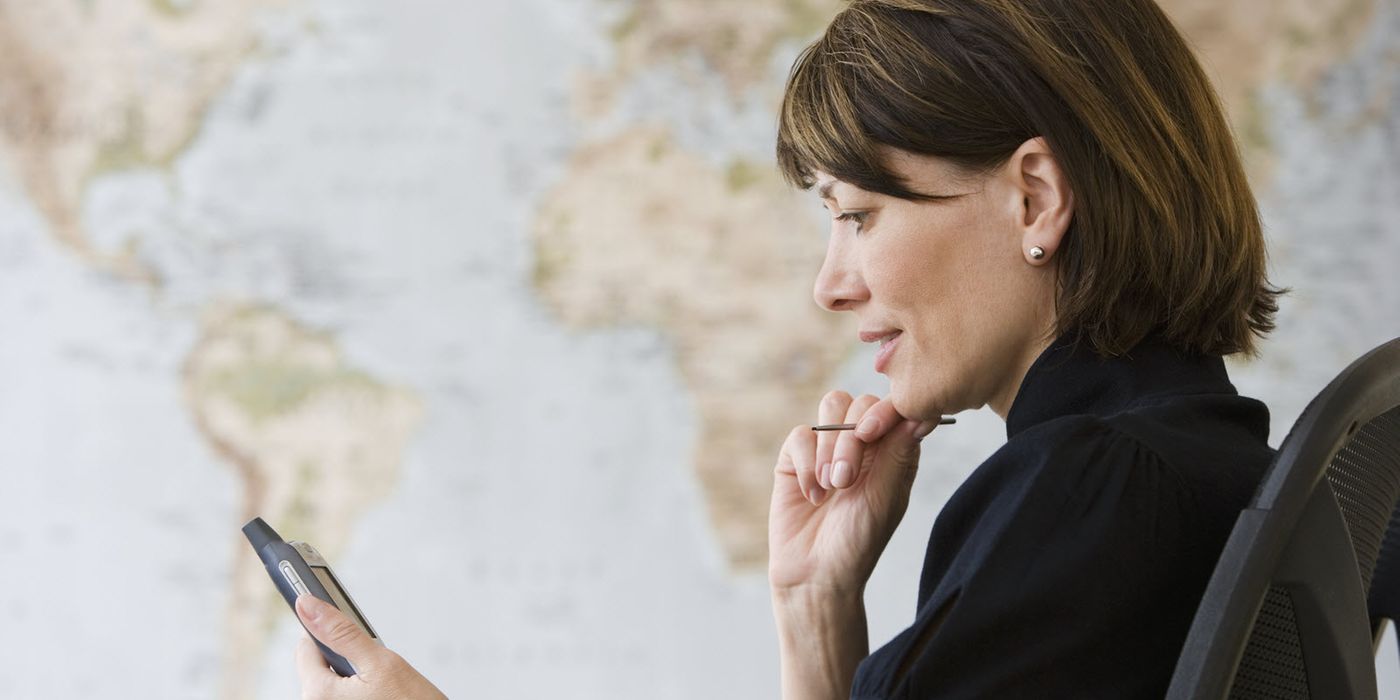 A woman reading her phone in front of a world map