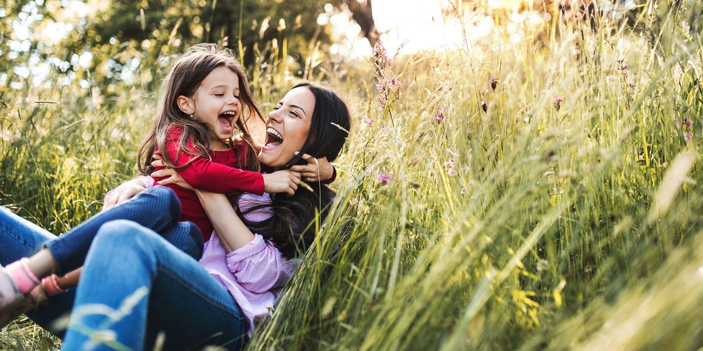 mother and daughter lying in field of flowers