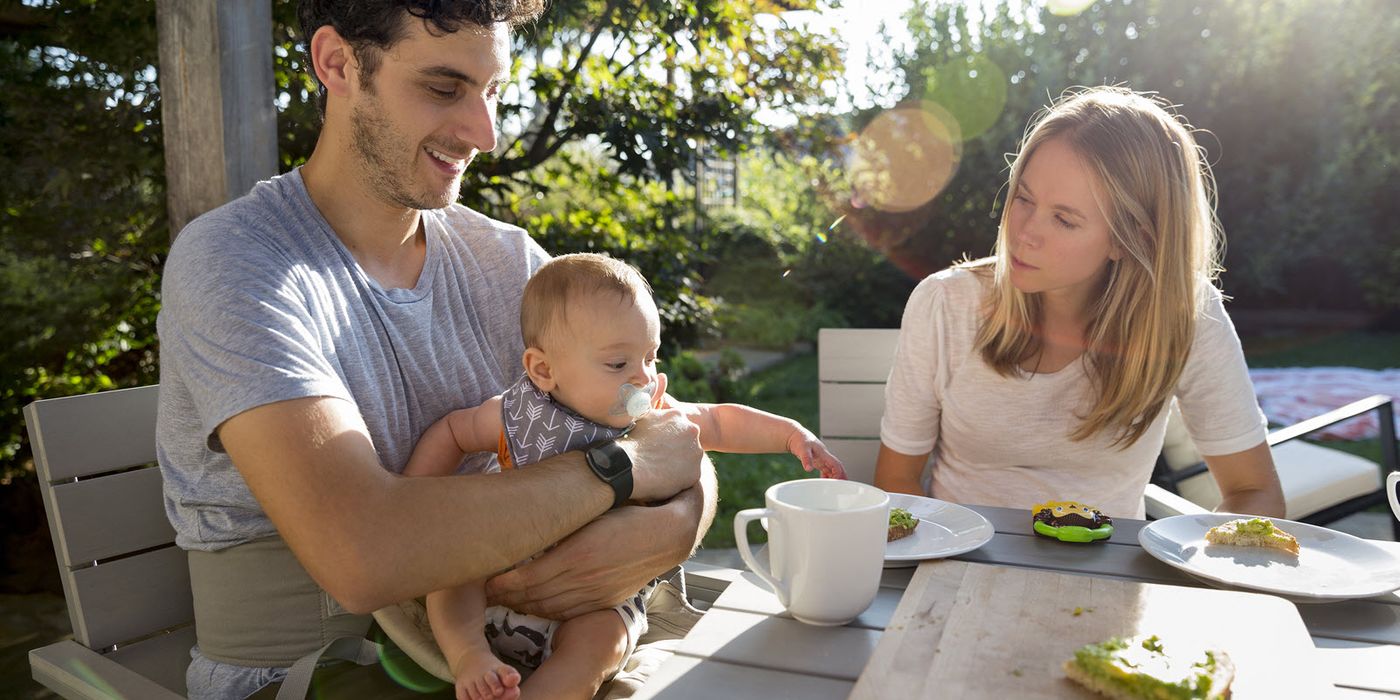 Parents eating outside discussing financial moves for their baby.