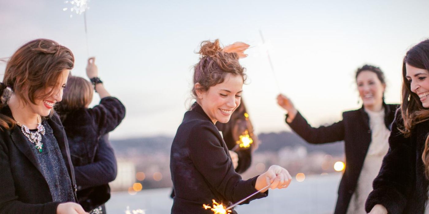 A group of friends waving sparklers around at a party.