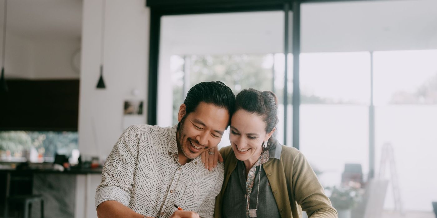 Cheerful couple looks at paperwork together in a kitchen