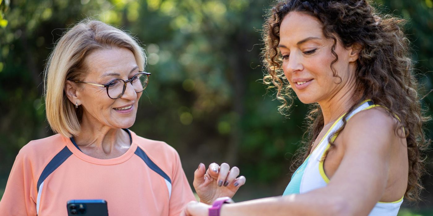 Two women talking and jogging in the public park. 
