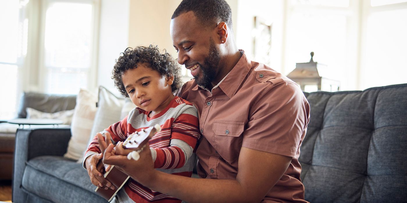 father and son playing ukulele on sofa