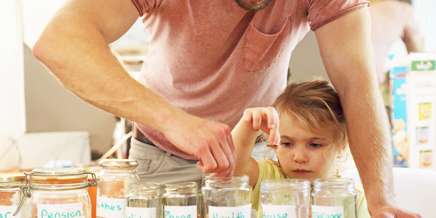 father and daughter financial planning with pennies in jars