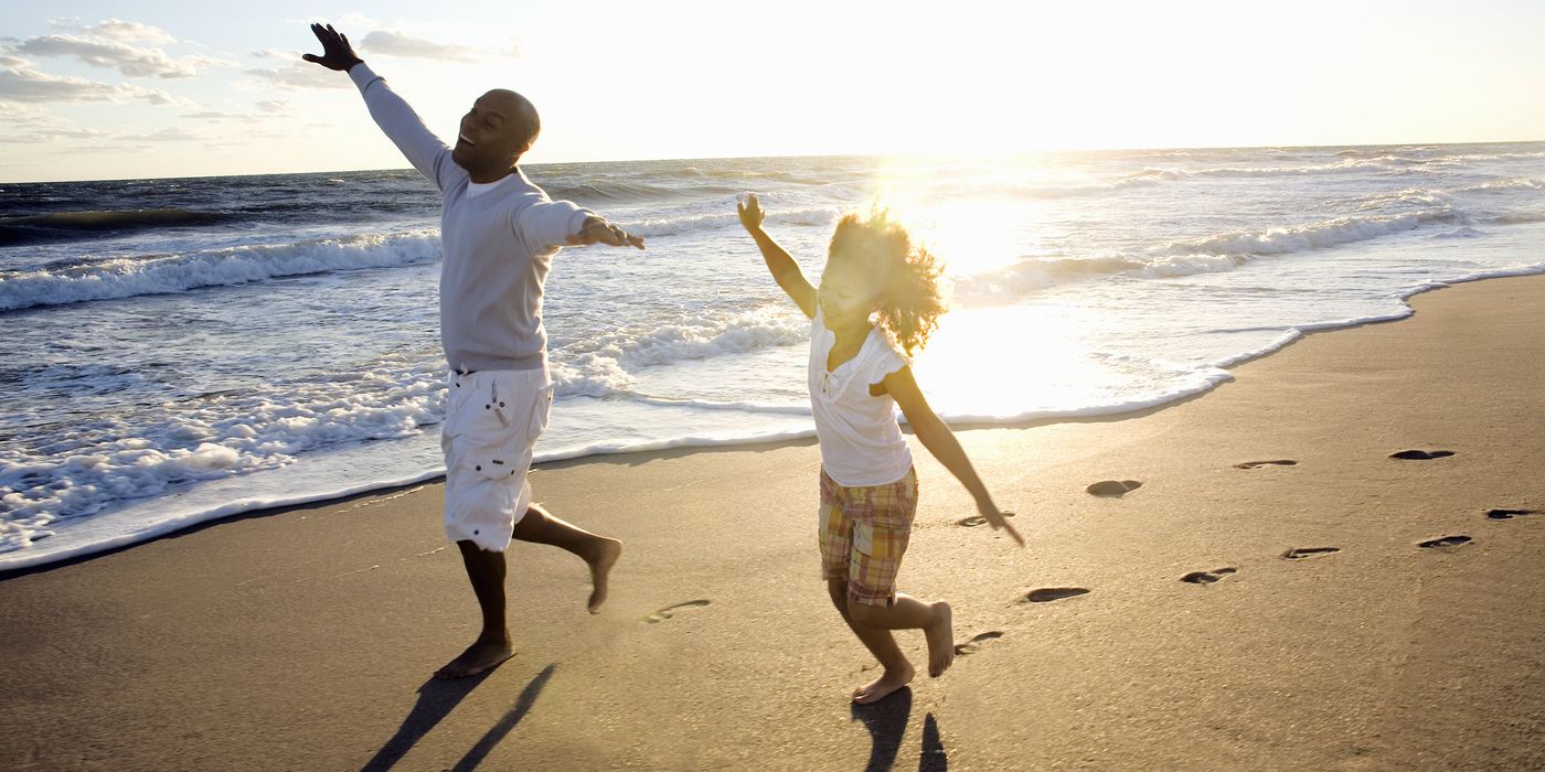 Father and daughter playing on a beach.