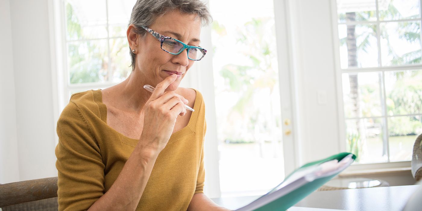 Woman at desk looking at a folder wondering about debt going into retirement