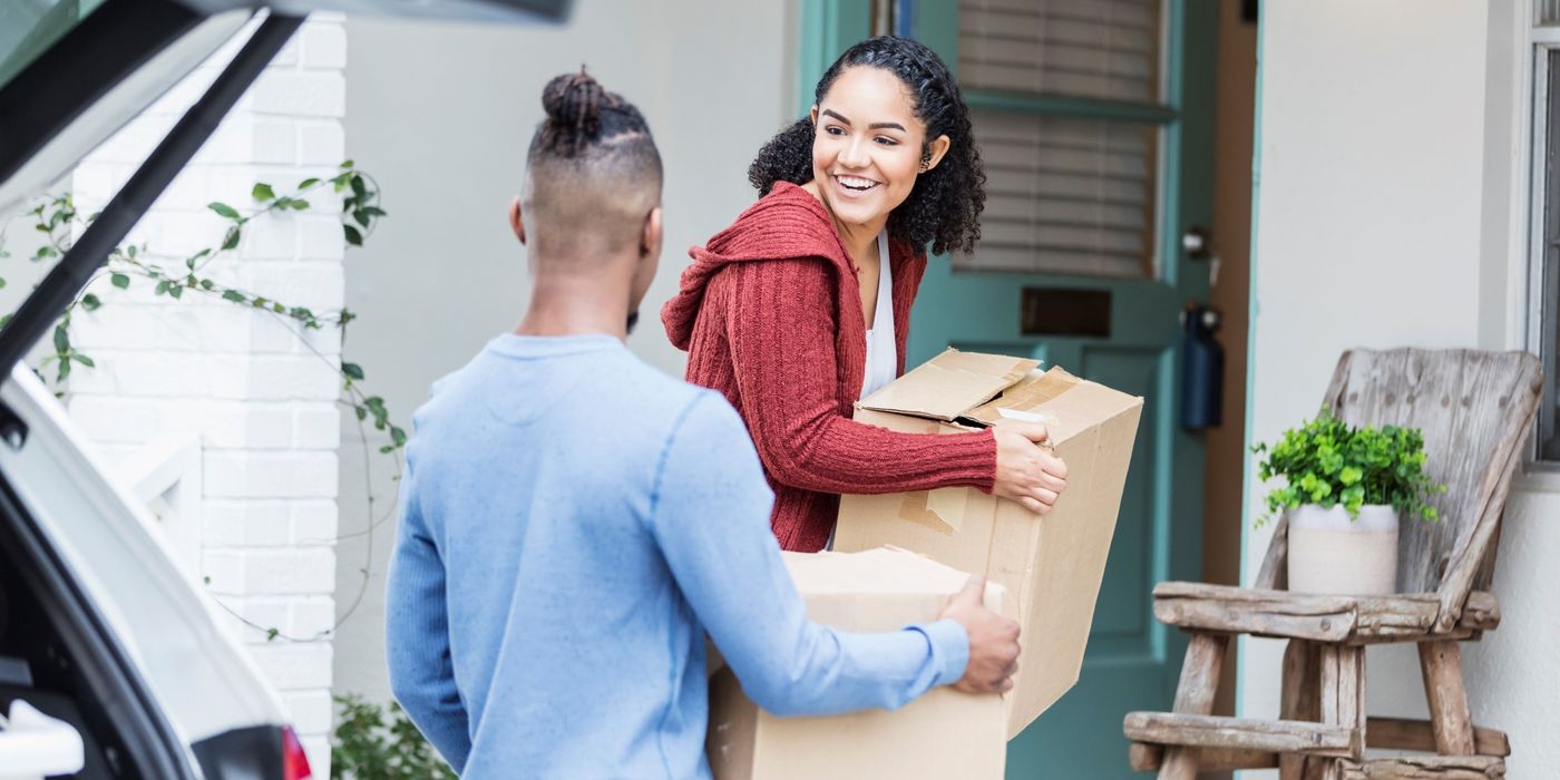 Couple carrying boxes into new house