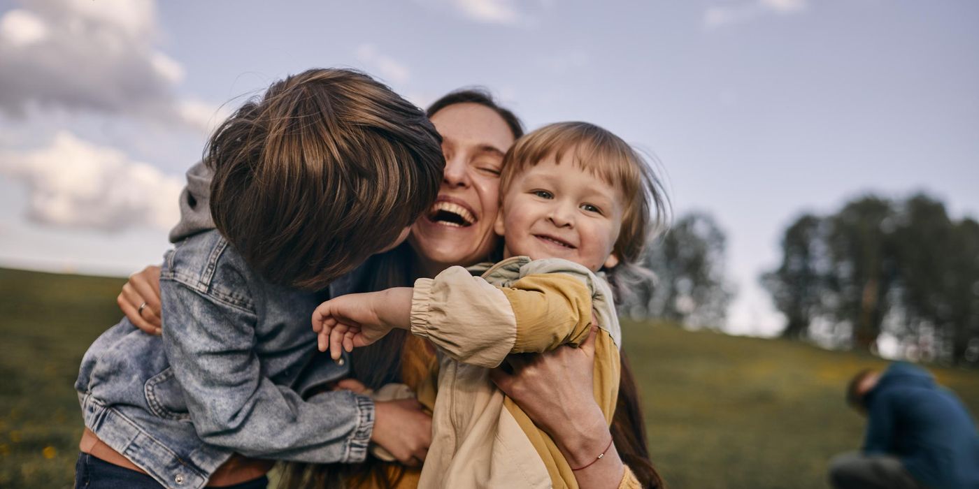 Happy mother hugging sons on a meadow